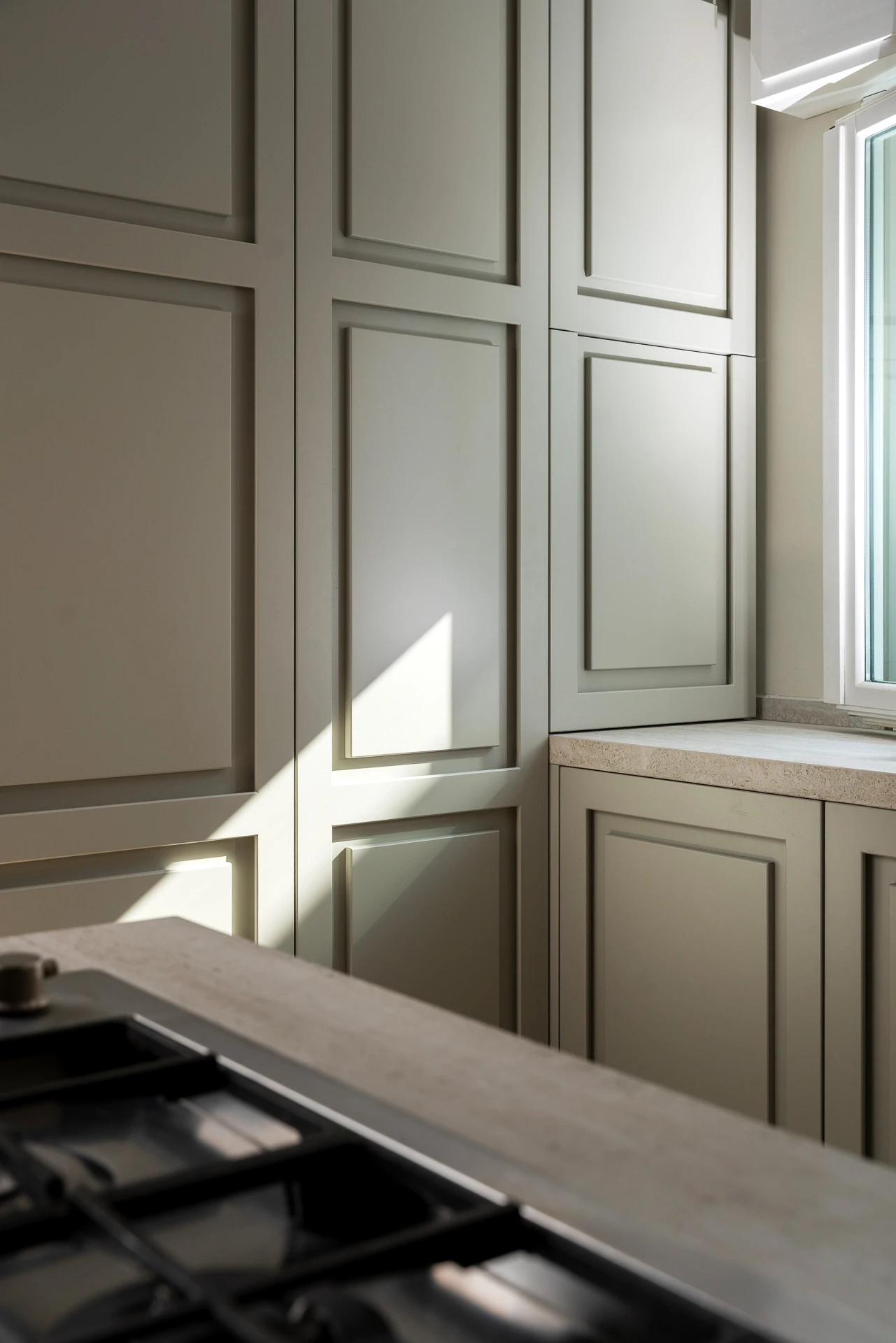 Full-height pantry in the custom kitchen, integrated with the hob and overlooking the window