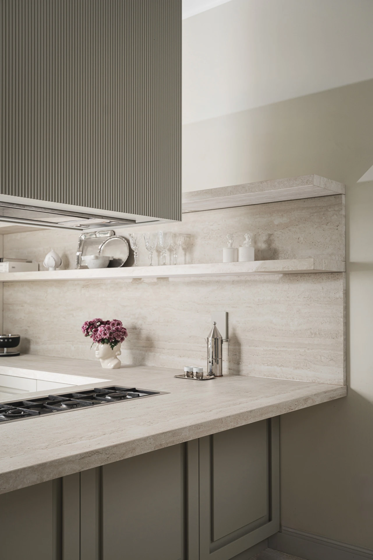 Handcrafted kitchen with a custom fluted hood, gas hob, and natural travertine backsplash