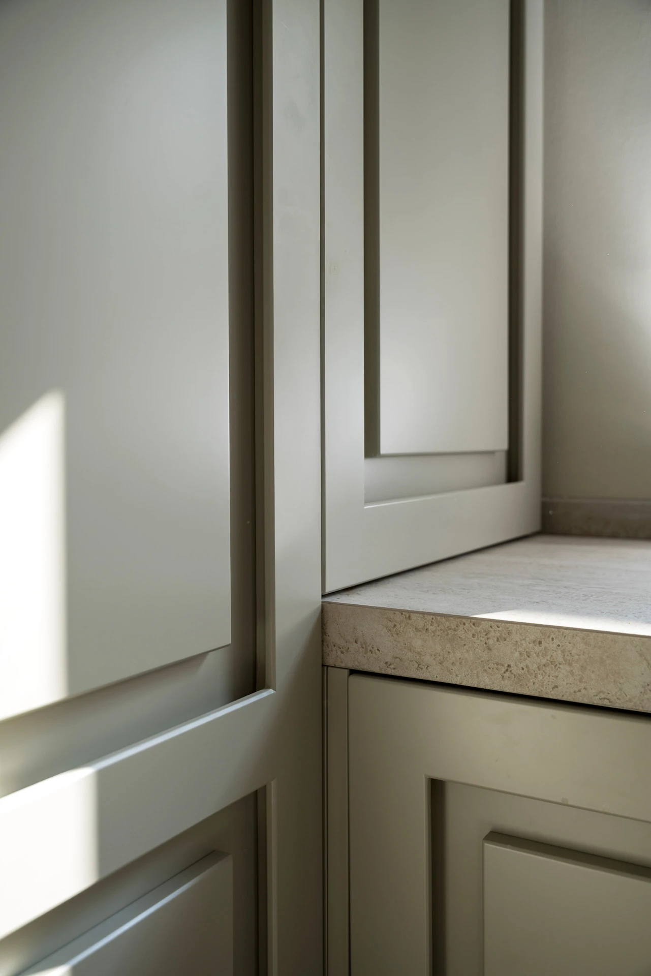 Progettazione cucina su misura: angolo della dispensa con ante a telaio e ripiano in travertino
